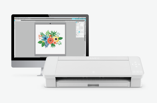 Image of a Cameo cutting machine in front of a computer displaying floral design software on the screen.